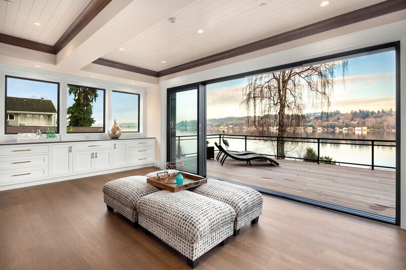 Large glass doors open to a second-story deck overlooking a Seattle-area lake. Home design and flor plan by residential architects from Architectural Innovations